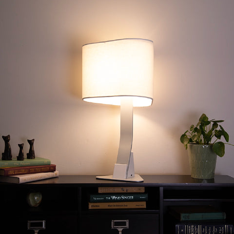 Brooklyn USB LED Desk Lamp on a small desk showcasing the lights' small footprint and ability to fit into small spaces. The light has a warm white 3000K glow to it. 