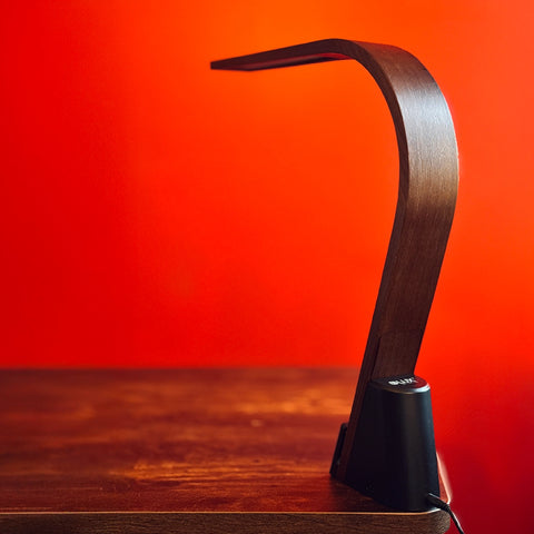 Brooklyn LED Task lamp in Black Walnut Wood finish on a wooden surface with a red background