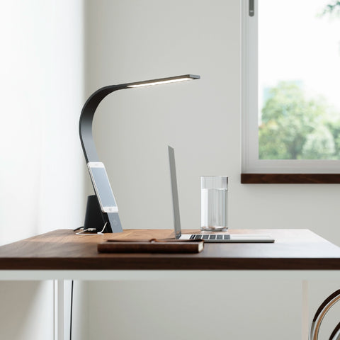 Brooklyn USB LED Task Lamp in Black Slate finish on a modern work desk with a phone charging via USB cord.