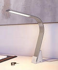 Side profile of Brooklyn USB LED Task Lamp in Brushed Aluminum next to a set of car keys on a minimalist desk with canvas art behind it.The USB-A port is visible as is the illuminated sleek LED panel.