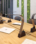 5 Brooklyn AC LED Task lamps on a wooden conference table with various computers plugged int to the universal ac sockets.