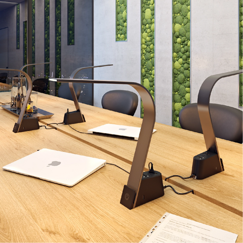 5 Brooklyn AC LED Task lamps on a wooden conference table with various computers plugged int to the universal ac sockets.