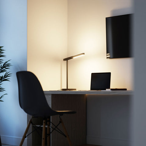 Highline USB LED Desk Lamp in use on a desk with a laptop and TV screen, showing warm upward and downward illumination