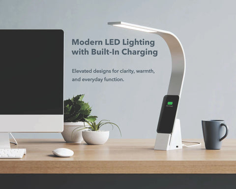 Modern Aluminum LED desk light charging a smartphone beside a computer on a home office desk.