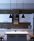 Three charcoal La Brea LED pendant lights hanging over a high top counter in a brick kitchen with white cabinets