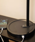 Close-up of the Highline USB LED Desk Lamp base with two USB-A charging ports and a phone charging